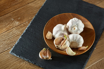 Garlic close up on wooden plate on rustic background, shallow depth of field, selective focus, macro