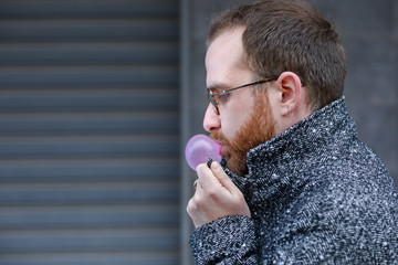 Cold Man with Beard Blowing a Bubble with a Bubblegum