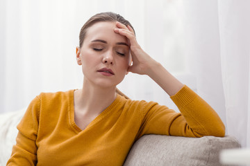 Leave me alone. Worried attractive doubtful woman putting hand on head while shutting eyes and...