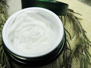 cosmetic cream for face care and rosemary leaves