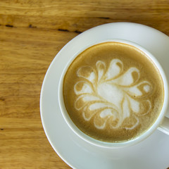 A cup of Cappuccino coffee in a white cup on wooden background