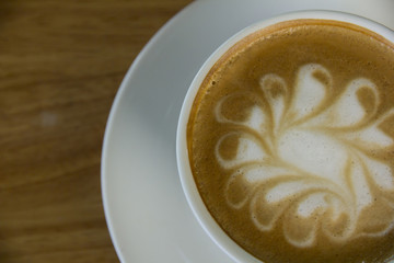 A cup of Cappuccino coffee in a white cup on wooden background