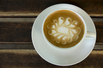 A cup of Cappuccino coffee in a white cup on wooden background