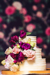 Three-tiered wedding cake decorated with beautiful flowers.