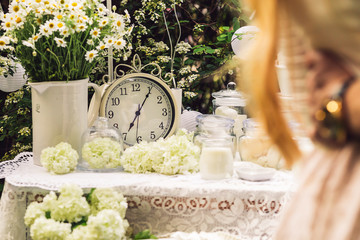 The table is decorated with white, with old clocks, candles, flowers, daisies in a vase. A couple is hugging each other.