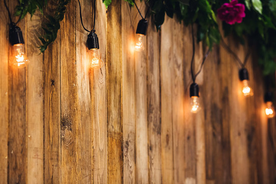 Wedding background of boards, decorated with light bulbs and flowers