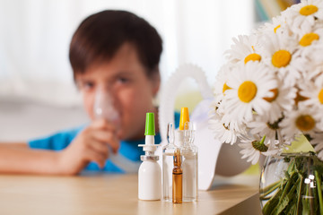 Obraz na płótnie Canvas Blurry boy using inhaler device with medication in the foreground