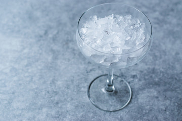 Crushed Ice in Cocktail Glass on Blue Surface.