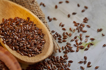 Flax seeds in bowl and flaxseed oil in glass bottle on wooden background, top view, close-up, selective focus