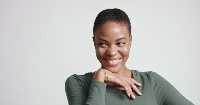 black woman with a short haircut in studio shootsmiling and wearing dress