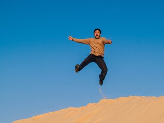 Fototapeta na wymiar 35-year-old man jumps from a desert dune