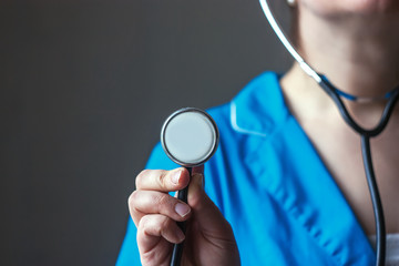 doctor in blue uniform holds a stethoscope - obrazy, fototapety, plakaty