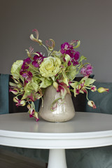 Bouquet of yellow roses with red flowers with buds in a vase on a white table