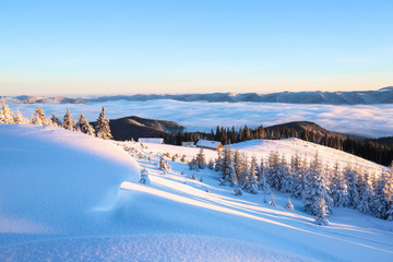 From the hills covered with snow, on which fall shades, opens a view on the mountain valley, where small huts are located, behind which stretched out spruce forest sprinkled with snow, dense fog.