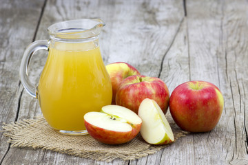 Apple juice and apples on wooden background