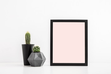 Photo frame mock up and a cactus on a white table.