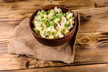 Ceramic bowl with russian traditional salad olivier on wooden table
