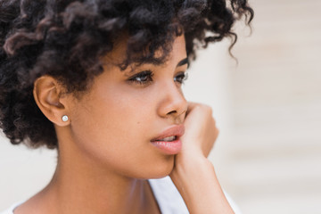Fototapeta premium Cropped close-up shot of beautiful young dark skinned woman wearing casual with sad, pensive, reflective look, against white wall background with copy space for your text or advertising content.
