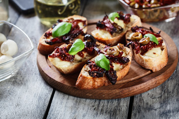 Appetizer bruschetta with sun-dried tomatoes, olives and mozarella.
