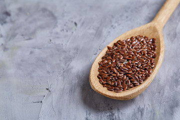 Flax seeds in wooden bowl and spoon on rustic wooden background, top view, shallow depth of field