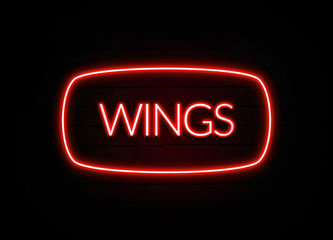 Wings neon sign on brick wall background.