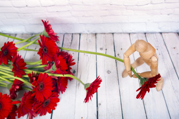 Wooden mannequin with red gerbera flower