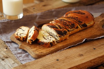 Fresh baked poppy seed roll and milk on the table  