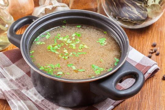Tasty meat broth in a dark cooking dish