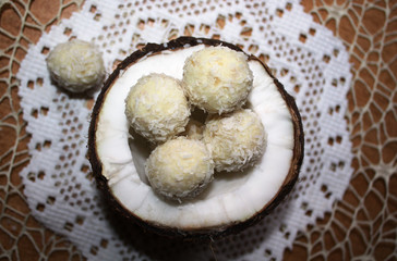 Coconut candy balls. A top view of a half of coconut, filled with organic, useful, dietary handmade candy from nuts and dried fruits. A useful snack.