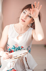 Young beautiful woman is engaged in embroidering a dagger on the embroidery frame in a colored...