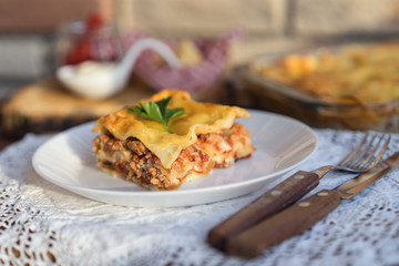 Classic hommade Lasagna with bolognese sauce on wooden table with lace tablecloth