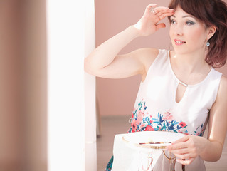 Young beautiful woman is engaged in embroidering a dagger on the embroidery frame in a colored...
