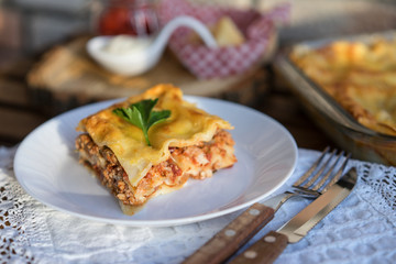 Classic hommade Lasagna with bolognese sauce on wooden table with lace tablecloth