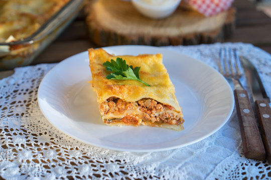 Classic hommade Lasagna with bolognese sauce on wooden table with lace tablecloth