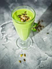 Healthy green smoothie with spinach, banana, mango and pumpkin seeds.