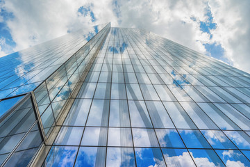 Modern office skycraper with cloudy sky on background.