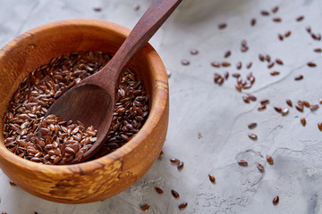 Flax seeds in wooden bowl and spoon on rustic wooden background, top view, shallow depth of field