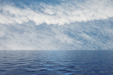 Calm sea with ripples leading to a blue sky with white clouds