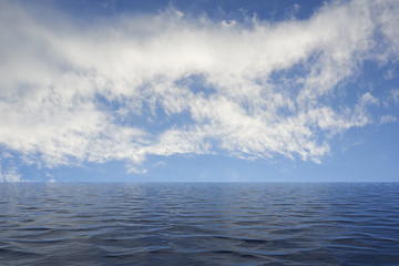 Obraz premium Calm sea with ripples leading to a blue sky with white clouds