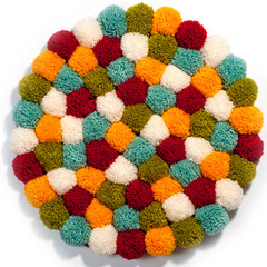 Mat of pompons made from multi-colored handmade yarn