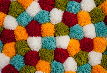 Fototapeta na wymiar Mat of pompons made from multi-colored handmade yarn