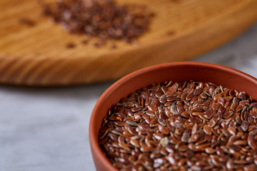 Flax seeds in wooden bowl and spoon on rustic wooden background, top view, shallow depth of field