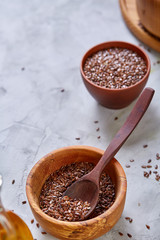 Flax seeds in wooden bowl and spoon on rustic wooden background, top view, shallow depth of field