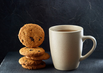 A glass cup of black tea with cookies on a dark greyish marble background. Breakfast background
