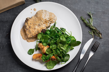 Fried beef entrecote with sauce and spinach salad, on a wooden background