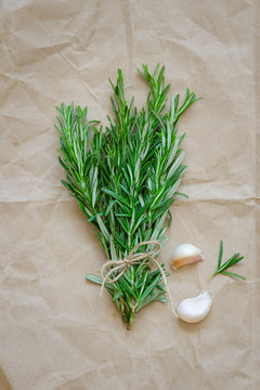 Bunch of rosemary with garlic on wrapping paper