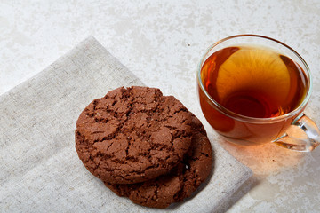 Top view closeup picture of tea in transparent cup with cookies and cotton napkin on white background, selective focus