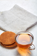 Top view closeup picture of tea in transparent cup with cookies and cotton napkin on white background, selective focus