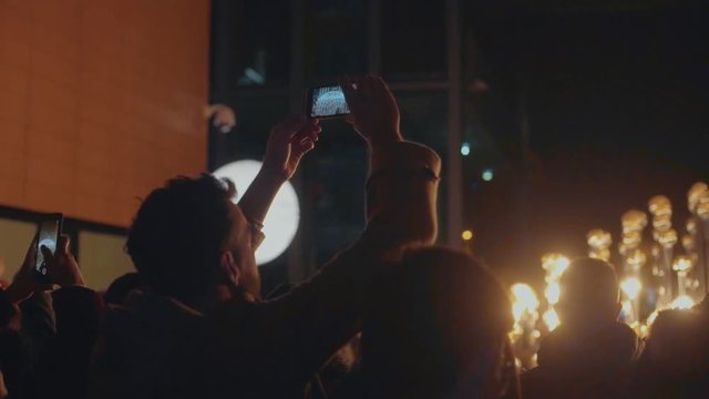 Beautiful shot of strangers and people united together during amazing concert or event at nighttime, use smartphones and cameras to capture moments and memories, forever young