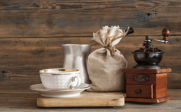 Coffee cup, coffee grinder, coffee brewing arabian Cezve, coffee beans on a wooden table